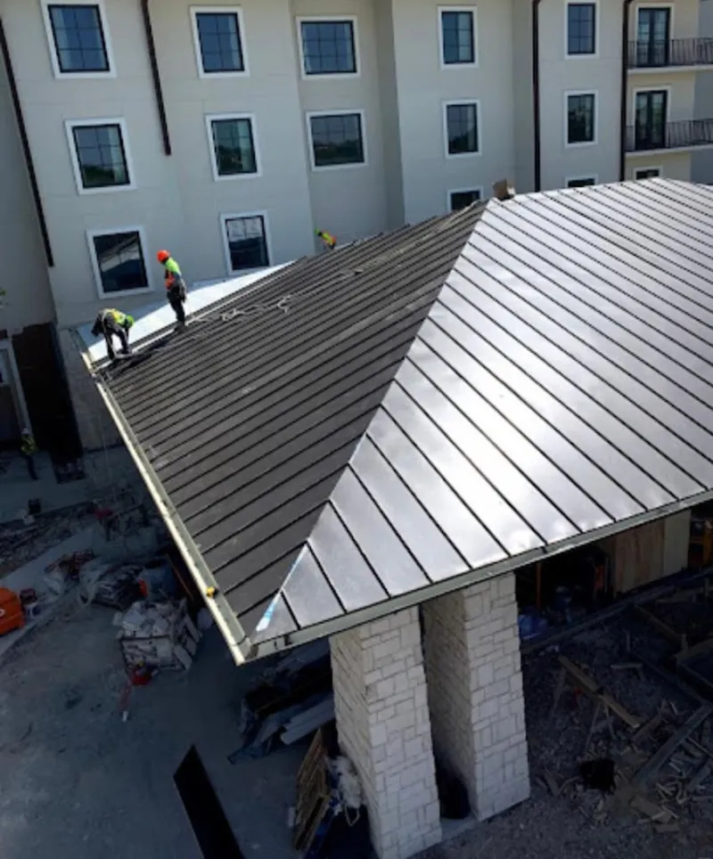 Crew installing standing seam metal roof panels on a commercial project in Turlock
